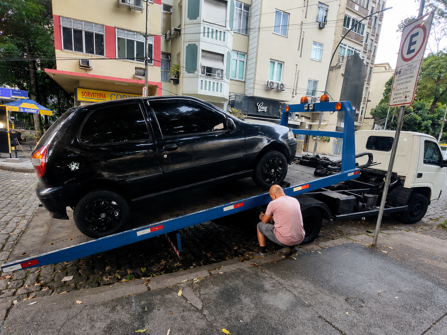 Carro preto sendo atendido no guincho em área urbana